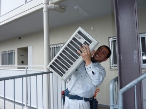 重たい室外機を担いで。